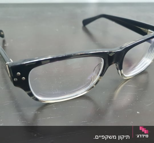 משקפיים שחורים עם מסגרת עבה על שולחן